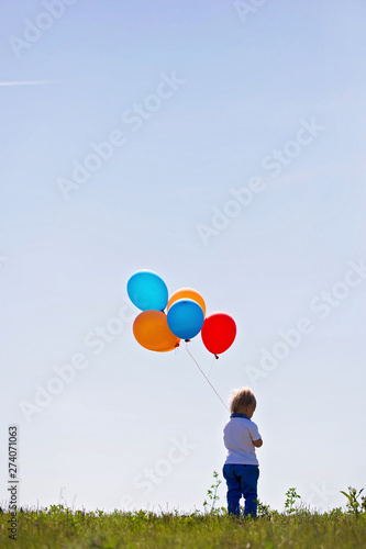 Little boy, toddler, child playing with colorful balloons in the park on kids day, sunny summer afternoon