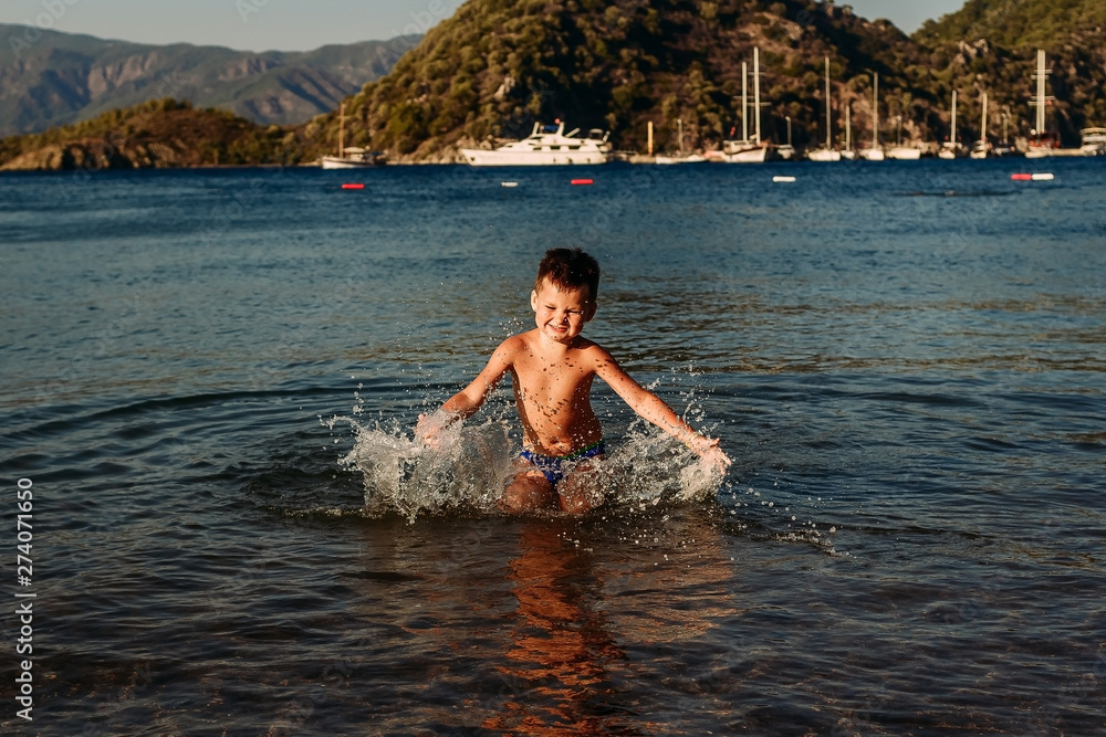 Fototapeta premium Five-year-old child splashes water into the sea