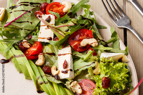 Obraz na płótnie Tasty and healthy salad with arugula, brie, cheese, avocado, cherry tomatoes, dry cranberry and cashews. Top view. The flat lay. Banner w salonie