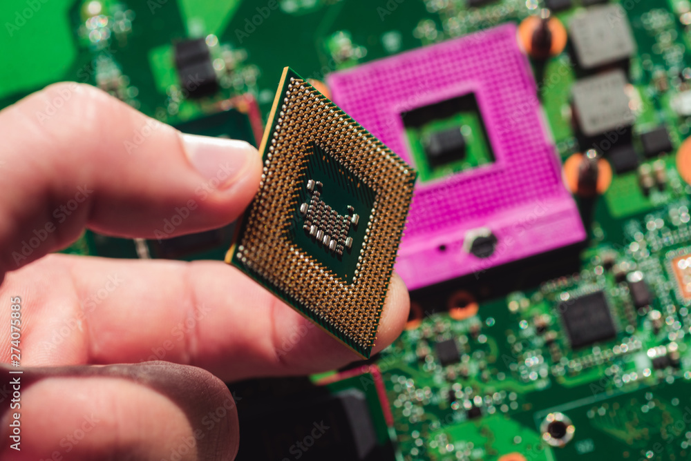 Laptop processor in the hands on the background of the motherboard macro photo