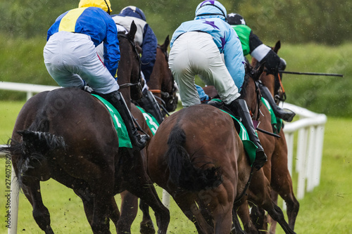 Close up on galloping race horses and jockeys in the rain © Gabriel Cassan