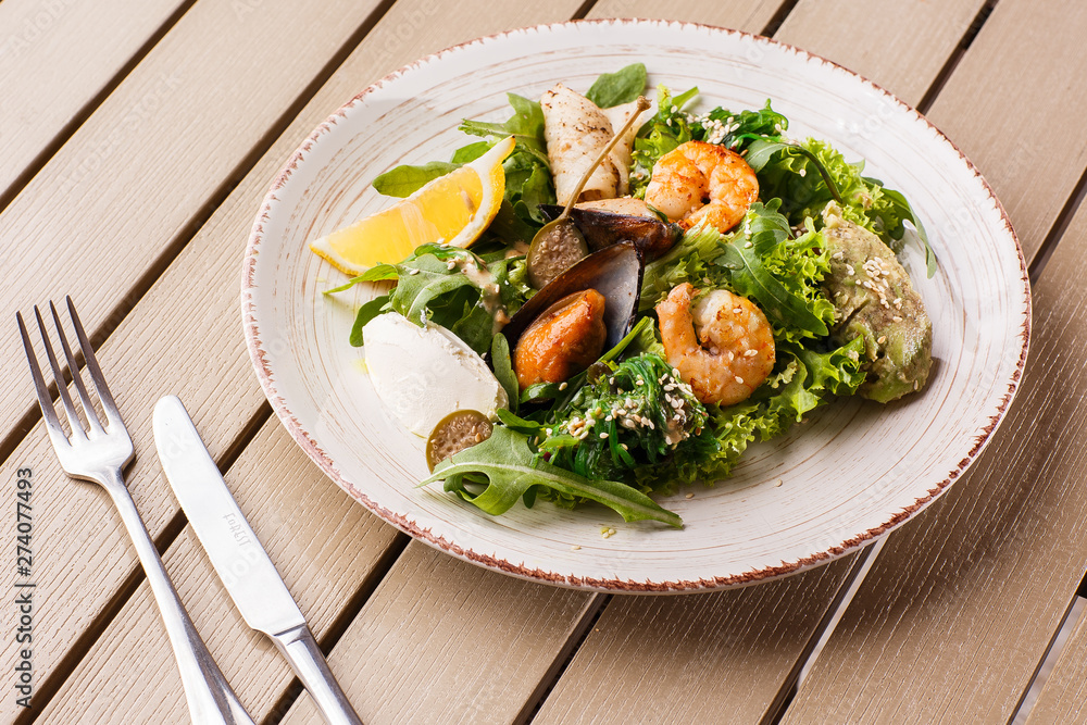 Healthy Salad. Recipe for fresh seafood. Grilled shrimps, mussels and squid, fresh salad lettuce and avocado puree. Healthy Eating. Wooden background Healthy Salad. Recipe for fresh seafood. Grilled shrimps, mussels and squid, fresh salad lettuce and avocado puree. Healthy Eating. Wooden background