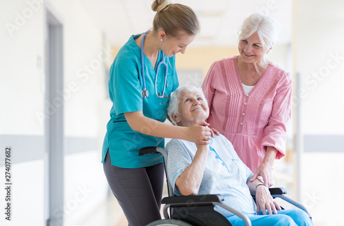 Elderly woman on wheelchair with her daughter and nurse © pikselstock