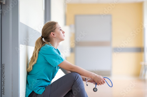 Bild auf Leinwand Tired female nurse in hospital corridor