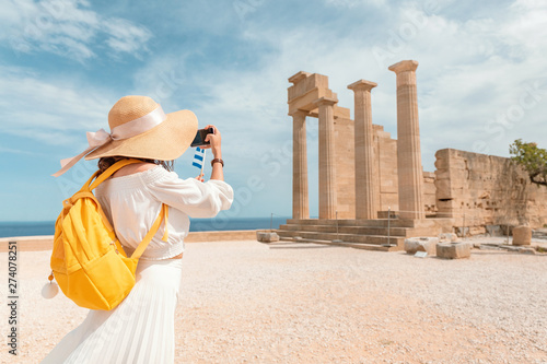 Tourist girl taking photos and selfie of tourist landmark of ancient Acropolis town. Travel destinations and sightseeing tours photo