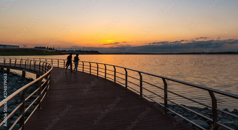 A couple on the bridge by the lake at sunset
