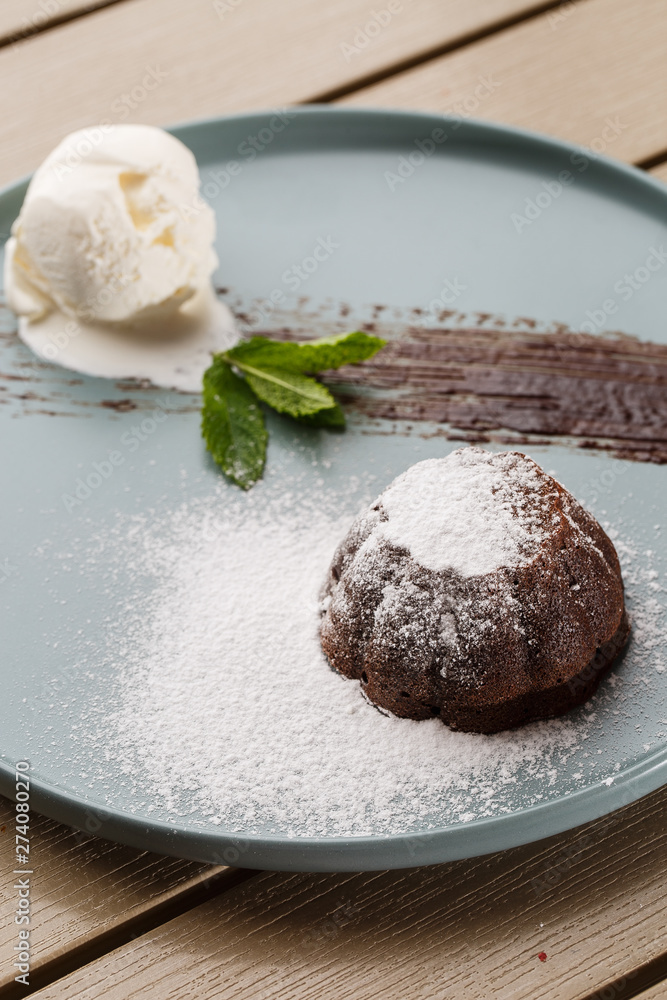 Delicious fresh fondant with hot chocolate and ice cream and mint served on plate. Lava cake recipe. Wooden background. Delicious fresh fondant with hot chocolate and ice cream and mint served on plate. Lava cake recipe. Wooden background.