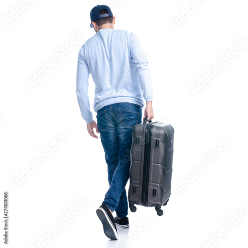 Man in jeans holding travel suitcase goes walking on white background isolation, back view