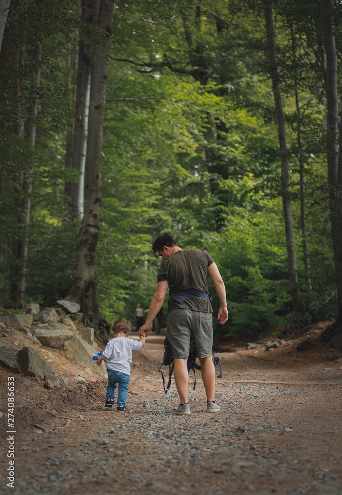 father and son walking along a path in the forest