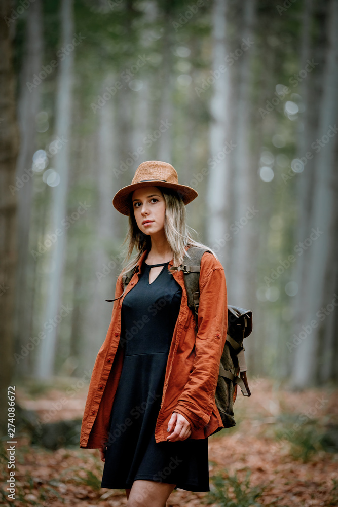 Style girl in hat with backpack in a summer time Mixed coniferous forest