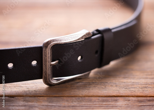 Belt close up. Black leather belt on a wooden surface.
