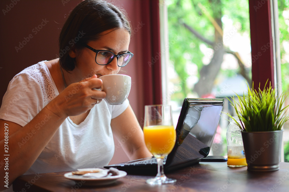 Woman websurfing on the net with laptop. Modern business woman in city cafe. Woman websurfing on the net with laptop. Modern business woman in city cafe.