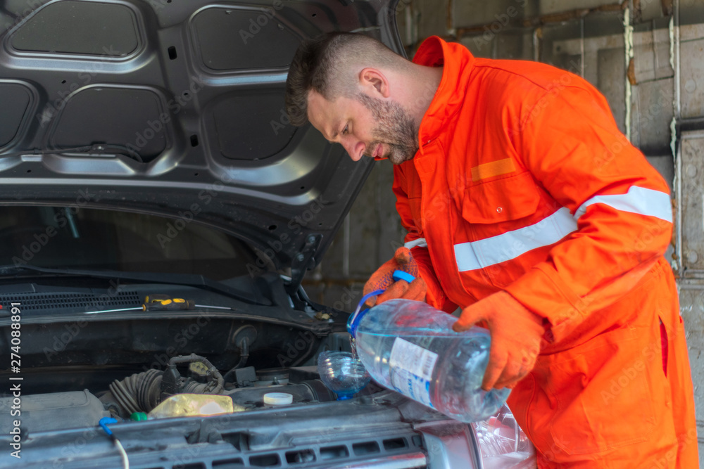 mechanic at the garage fixing a car. service and maintenance. car repair. fix a car. Hot bearded man in robe mechanic at the garage fixing a car. service and maintenance. car repair. fix a car. Hot bearded man in robe
