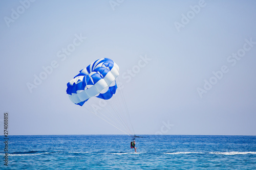 Couple of tourists flies on a blue and white parachute