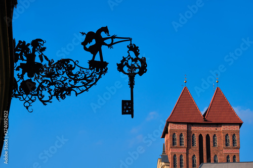 Medieval hanging shop signs with church towers in Torun, Poland photo