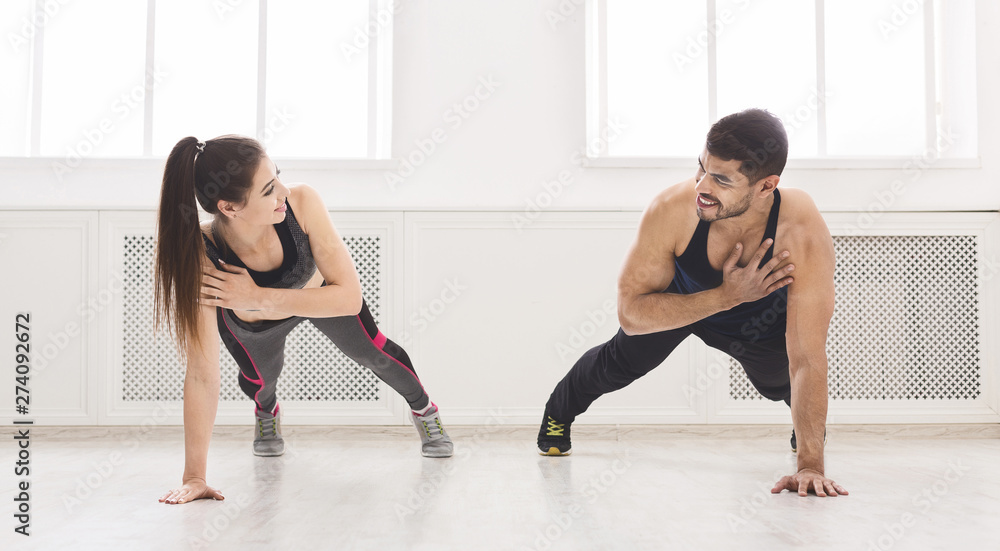 Young fit couple standing in plank with one hand