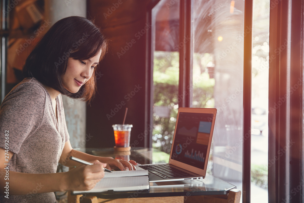 Isolated mockup image of laptop and Young business woman in casual dress sitting at table in cafe and writing in notebook. Isolated mockup image of laptop and Young business woman in casual dress sitting at table in cafe and writing in notebook.