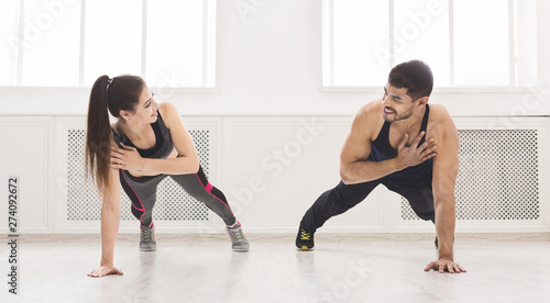 Young fit couple standing in plank with one hand © Prostock-studio