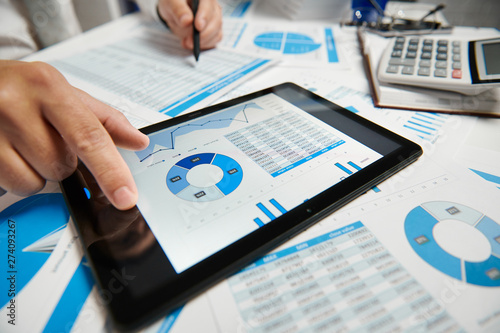 Fotografie Businessman working and calculating, reads and writes reports