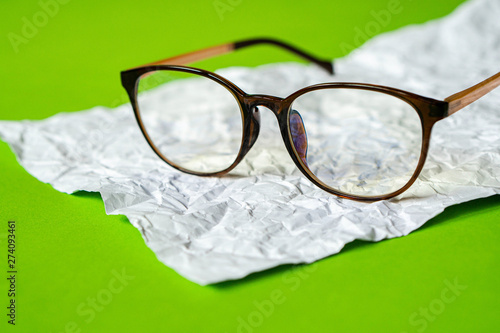 Fototapeta Naklejka Na Ścianę i Meble -  White crumpled paper and green paper. eyeglass concept.