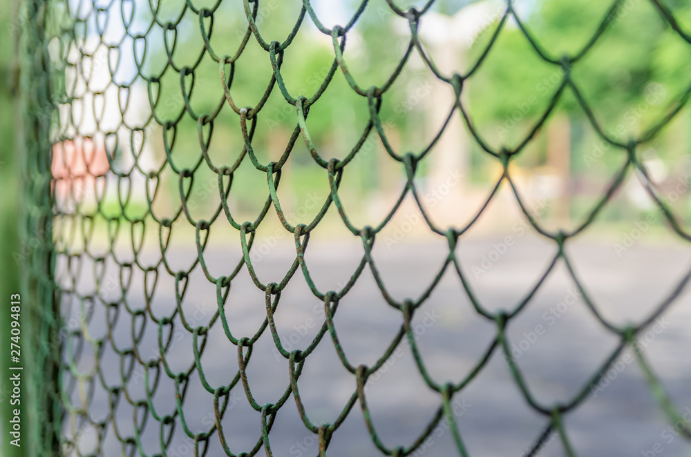 Fototapeta premium Old metal fence chain links on green background, metal mesh
