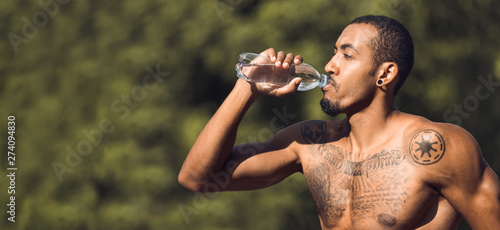 Shirtless Muscular Man Drinking Water After Training In Park