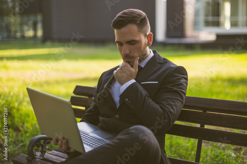 Worried businessman using laptop while sitting outdoor.Toned image.