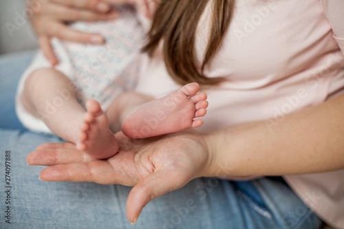 Close-up. The legs of the little baby in her mother's arms. Motherhood.