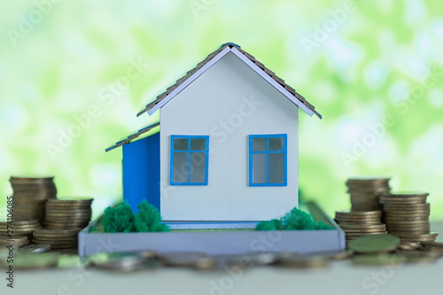 Model of house with coins on wooden table, saving money for buy home concept