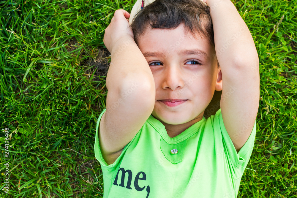 cheerful smiling boy lying on the grass in the summer cheerful smiling boy lying on the grass in the summer