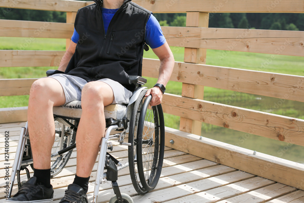 Obraz premium Disabled young man on a wheelchair holding and turning wheels with hand