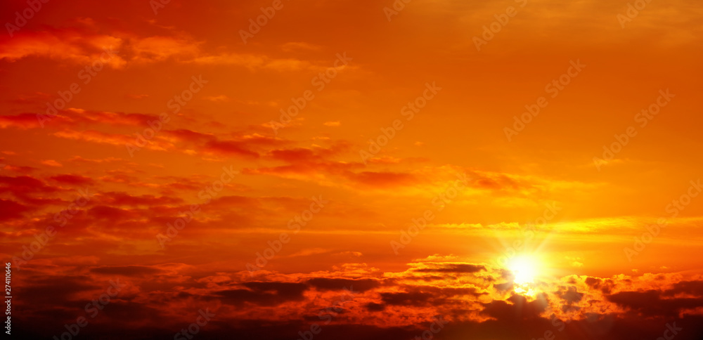 Beautiful cloudscape of orange colored sunset sky with shining sun
