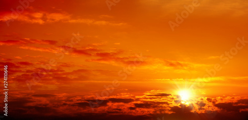 Beautiful cloudscape of orange colored sunset sky with shining sun © jokerpro