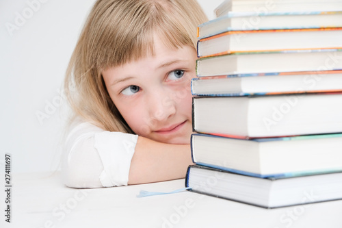 Beautiful little girl hiding behind a stack of books