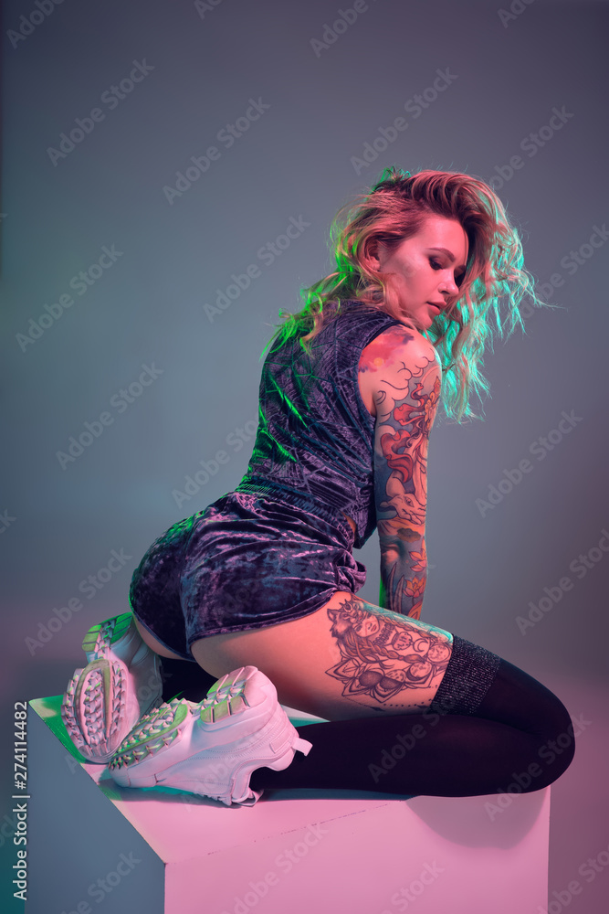 Young fitness blonde woman wearing blue velour booty shorts posing on  camera, sits on top of big cube, back view Stock Photo | Adobe Stock