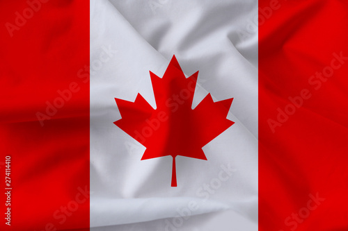 beautiful national flag of Canada on soft silk with soft folds, close-up, copy space