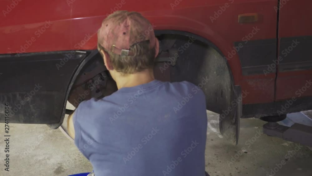A mechanic repairs a car at a service station A mechanic repairs a car at a service station