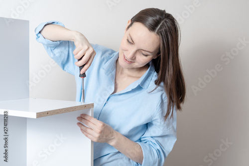 portrait close-up of a young independent woman with a screwdriver collects furniture