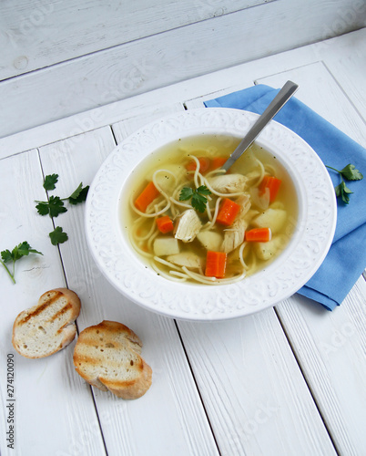 Russian chicken soup with carrots, potatoes, noodles on a light background. view top