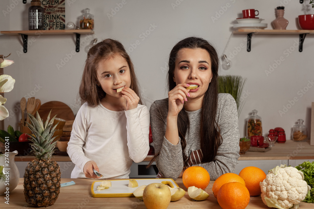 Mother and her daughter are doing a fruit cutting and having fun at the kitchen. Mother and her daughter are doing a fruit cutting and having fun at the kitchen.