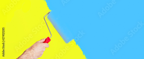 Hand holding a roller drawing,yellow and blue background photo