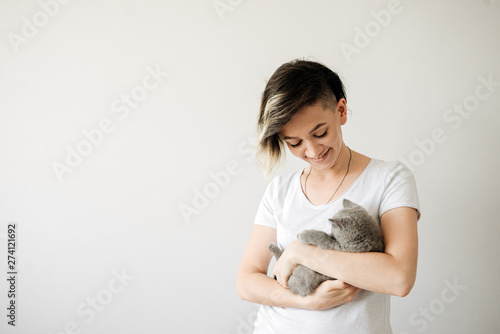 Beautiful young woman with cute cat resting at home. The British Shorthair