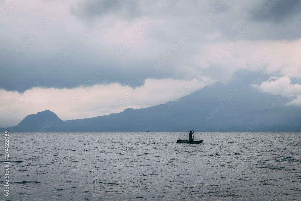 man on kayak on lake in front of mountain man on kayak on lake in front of mountain