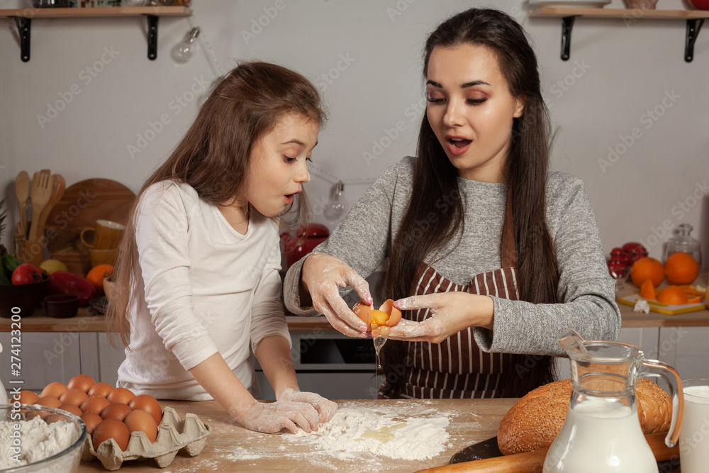 Mother and her daughter are baking a bread and having fun at the kitchen. Mother and her daughter are baking a bread and having fun at the kitchen.