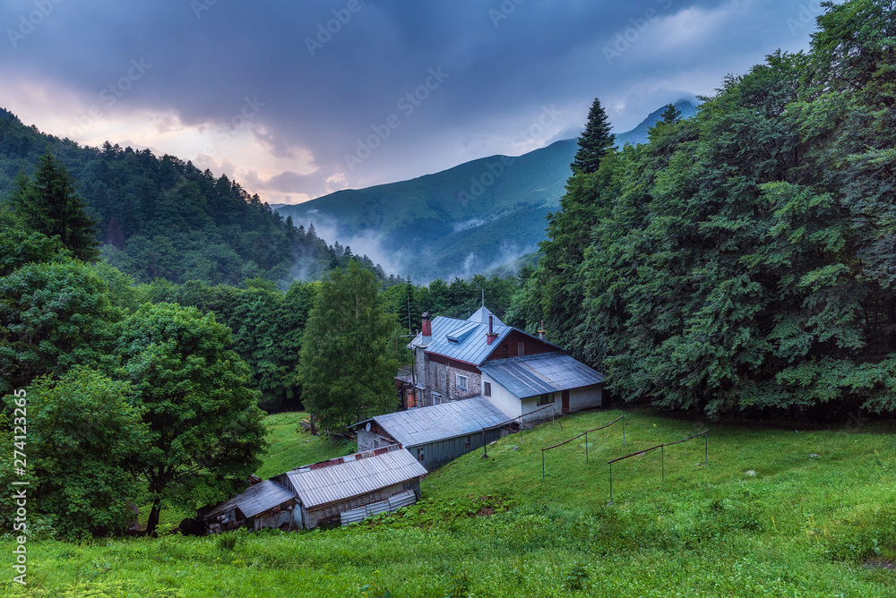 Vasil Levski mountain hut in Old mountain (Stara planina), Old river national park, Bulgaria. Summer landscape, green forest with dark rainy sky and puffy clouds during sunset