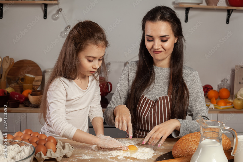 Mother and her daughter are baking a bread and having fun at the kitchen. Mother and her daughter are baking a bread and having fun at the kitchen.