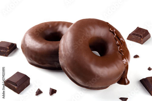 Delicious fresh chocolate donuts with pieces of chocolate on white background. Appetizing tasty glazed donuts ready to eat among pieces of chocolate on white background.