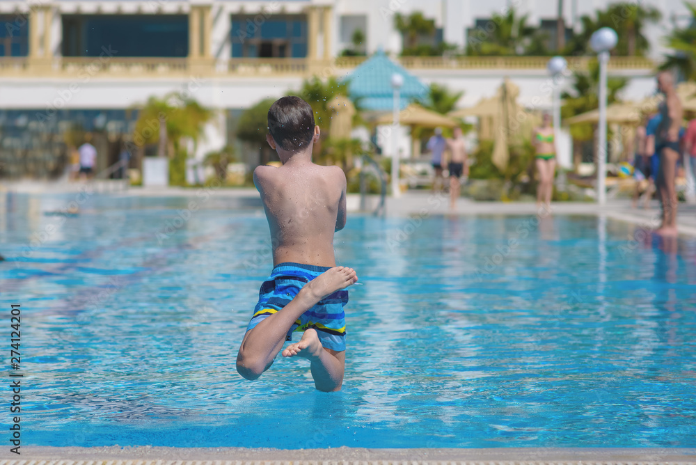Boy having fun making fantastic jump into swimming pool.