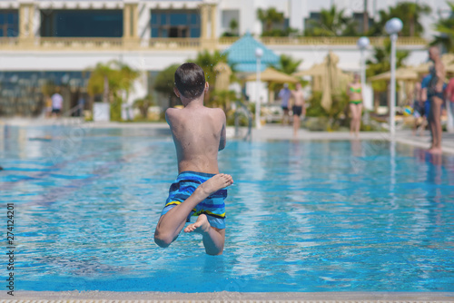 Boy having fun making fantastic jump into swimming pool. © Artem