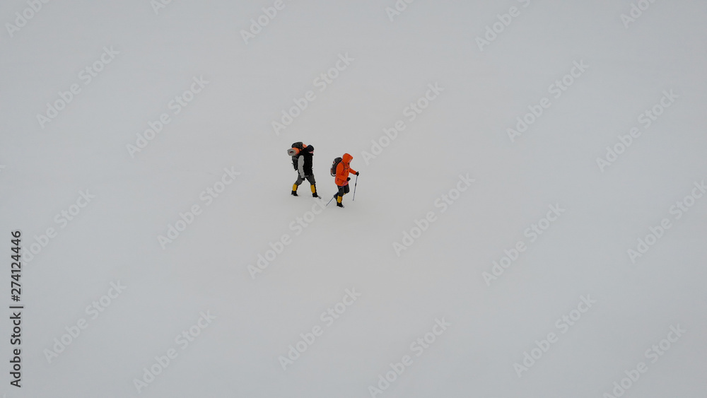 Fototapeta premium Aerial View of Two People Trekking in Snow